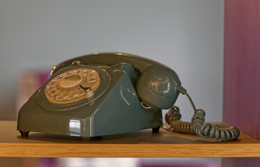 an old retro vintage rotary dial telephone stands as decoration in a dark cupboard, the spiral...