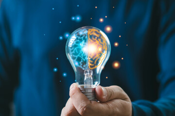 Hand holding a glowing light bulb with innovative ideas. Concept of creativity, brainstorming, and...