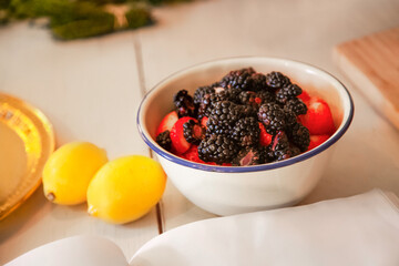 Chef preparing blackberries and strawberries with lemons on table