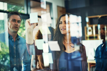 Moodboard, sticky notes and writing with business people in office together for brainstorming. Glass wall, meeting and training with professional colleague group in workplace for strategy discussion