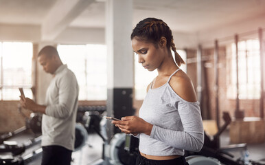 Fototapeta premium People, cellphone and woman in gym, wellness and social media with chatting. Health, athlete and girl with smartphone, fitness or internet with digital app for exercise routine, contact or connection