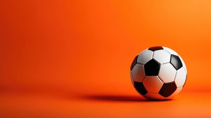 Fototapeta premium Sports theme stock photo with a traditional soccer ball, placed on a vibrant orange background, professional studio lighting.