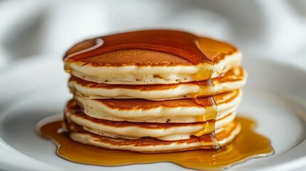 A stack of fluffy pancakes drenched in golden syrup. The perfect breakfast treat!