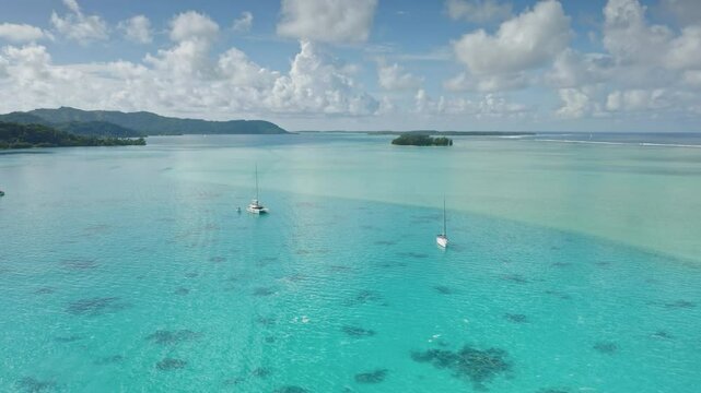 Aerial view of luxury sailboats gliding through the serene turquoise coral reef waters of Bora Bora tropical island, framed by lush green islands and clouds blue sky. Exotic travel vacation getaway