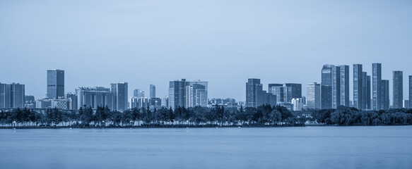 Obraz premium Serene Urban Skyline Reflection: A Panoramic View in Tranquil Blue
