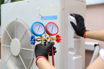 Electrical technician conditioning using manifold gauge measuring tool checking refrigerant pump...
