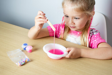 Cute Caucasian girl is making slime from scratch. Children education. Homeschooling. Child...