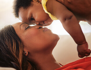 Love, mother and kiss baby on sofa for relationship, bonding together and child development. Black...