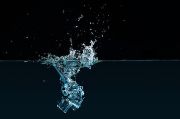 Clear ice cubes dipping into water causing a splash