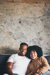 Portrait, black couple and smile on couch at house for love, weekend romance and marriage relationship. Happy, people and partner with embrace for connection, commitment and bonding together of break
