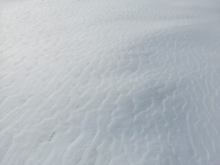 Aerial view of wind-blown snow waves in a snow-covered field - Vue aérienne de vagues de neige formées par le vent dans un champs enneigé
