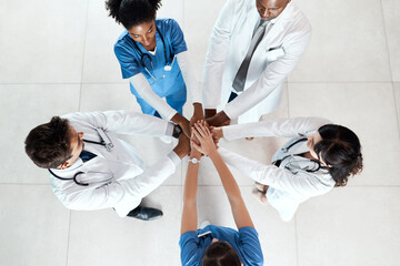 Doctor, meeting and hands together with unity above at hospital for collaboration or health campaign. Top view, healthcare employees or medical team piling with circle for group motivation at clinic