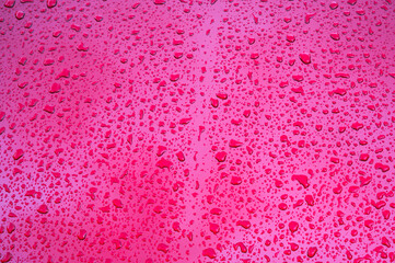 abstract red background with the texture of rain drops on shiny metallic surface closeup