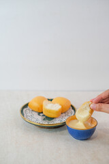 Golden Crispy Fried Mantou With Fluffy Center Being Dipped Into Creamy Cheese Sauce By Hand On Elegant Plate And Clean White Background.