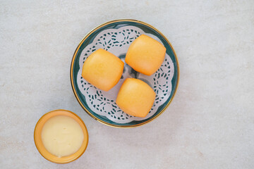 Crispy Fried Mantou Buns Arranged On Stylish Plate With Decorative Doily And Served With Creamy Cheese Dipping Sauce In A Bowl On White Surface.