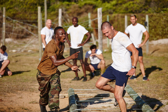 Men, fitness or instructor with drill for military training, bootcamp or physical activity on grass field. Male people, trainer or superior officer with team, army or soldiers for obstacle course