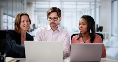 Diverse business team collaborating happily on laptop