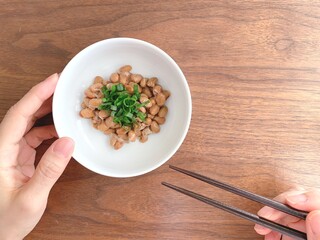 青ネギ入り納豆と箸を持つ女性の手元