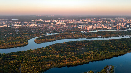 Kyiv city sunset skyline and Dnipro river aerial drone view from above, Kiev hills, pedestrian Park bridge and Dnieper river cityscape in autumn, Ukraine