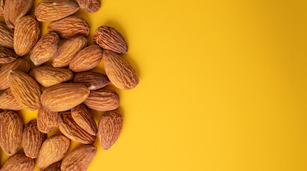 Warm brown hues of the almond nuts. Food concept.  Almonds on orange background with space for text