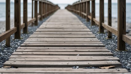 Fototapeta premium Wooden walkway extending towards the water with railings and pebbles along the sides on a cloudy day