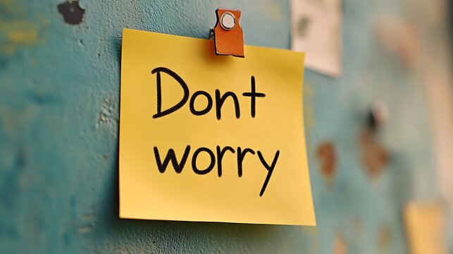 Yellow sticky note on a metal surface with the handwritten message "Don't worry".