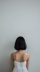 Obraz premium Woman in a white dress standing against a wall with self-improvement magazine in realistic photography setting