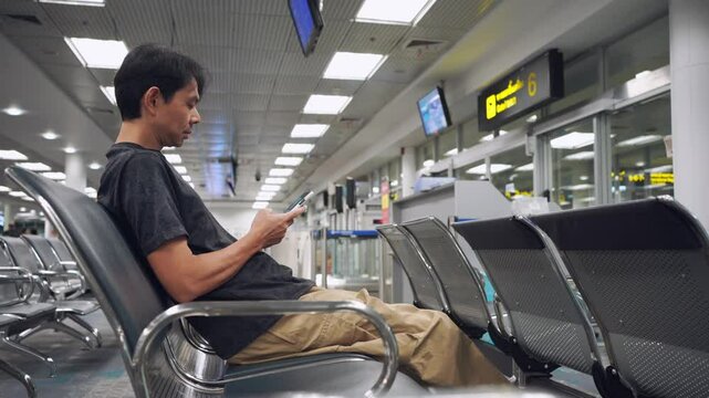 business and solo travel concept with asian man sit on seat and work with tablet in airport 
