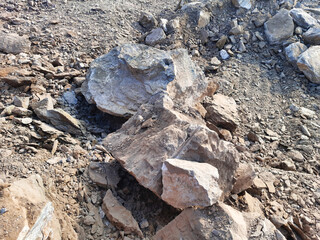 Obraz premium Workers uncover a significant rock formation during excavation at a construction site, amidst piles of loose soil and gravel