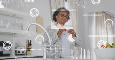 Image of data processing over senior african american woman drinking coffee in kitchen