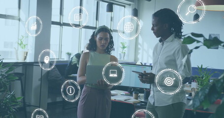 Image of icons over diverse business people using laptop in office