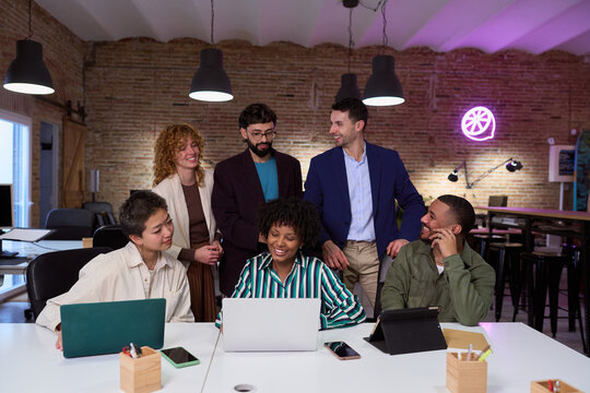 Marketing team sharing ideas and working on laptop in modern office