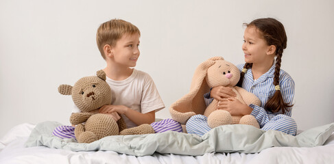 Cute little children with knitted toys sitting in bedroom