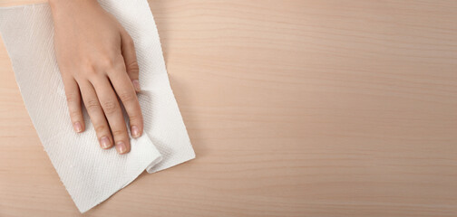 Woman wiping wooden table with paper towel
