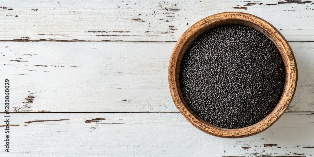 Poster black poppy seeds in a rustic wooden bowl centrally positioned on a distressed white wooden surface 