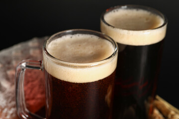 Mugs of tasty kvass on black background