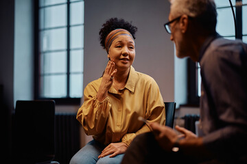 Mature woman talking to counselor during therapy session at mental health center.