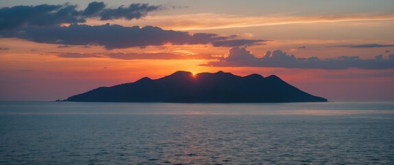 Fototapeta premium Sunset over a tranquil island silhouetted against colorful sky with reflection on water near coast Copy Space
