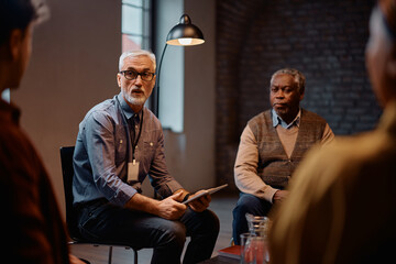 Mature mental health professional talking during group meeting at community center.