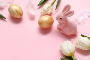 Bunny figurine with Easter eggs, feathers and tulips on pink background