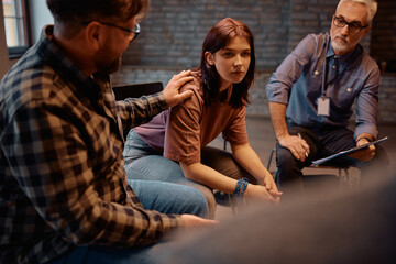 Supportive people encouraging young woman during group therapy meeting at community center.