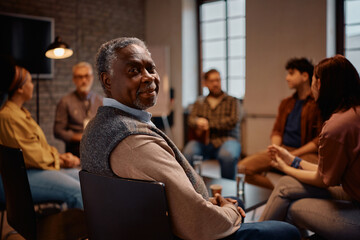 Black senior man participating in mental health counseling at community center looking at camera.