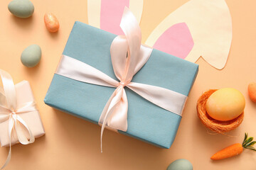 Easter eggs with gift boxes and paper bunny ears on orange background