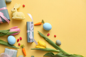 Easter eggs with gift boxes, tulip flowers and bunny on orange background