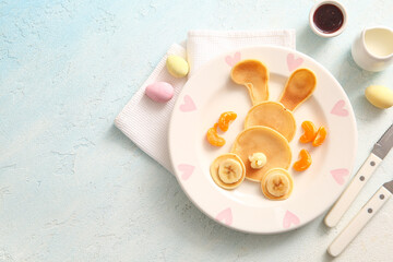Funny Easter bunny pancakes with banana and painted eggs on light blue background