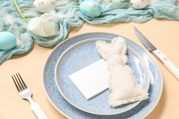 Stylish festive table setting for Easter celebration with blank card on beige background