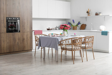 Dining table with Easter eggs, tulips and dinnerware in kitchen