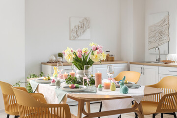 Modern interior of festive decorated kitchen with Easter table setting, pictures and chairs