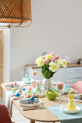 Stylish Easter table setting and vase of flowers in room