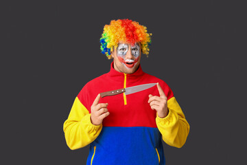 Young man as crazy clown with knife on black background